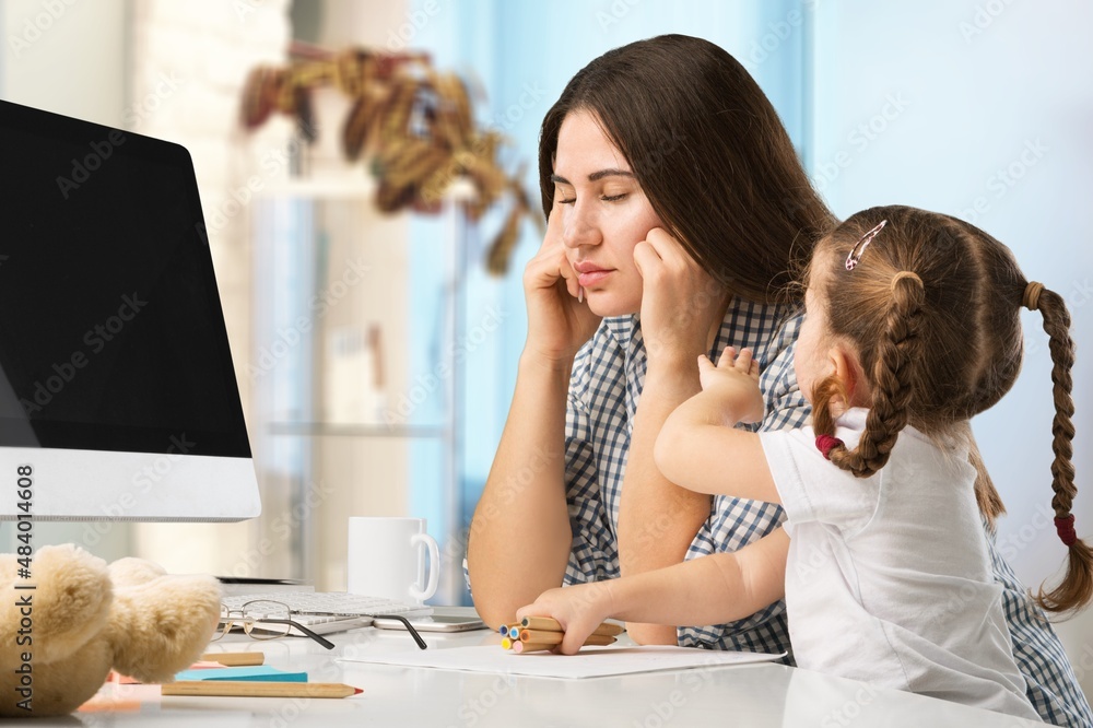 Happy busy mother working with a child on laptop