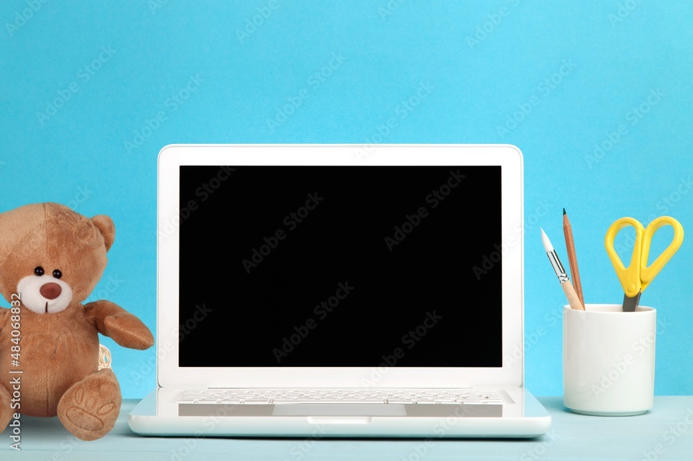 Open laptop at childrens workplace with toy bear. Back to school online learning concept