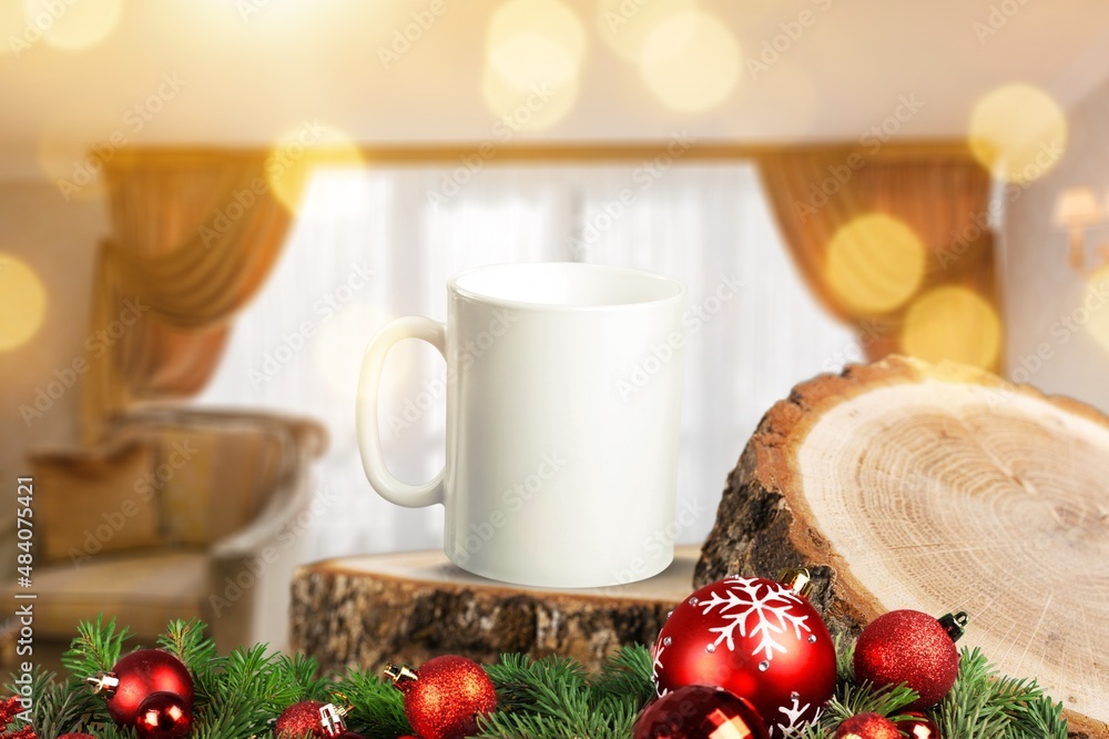 White mug on a wooden background with bright lights in the background. New Year and Christmas.