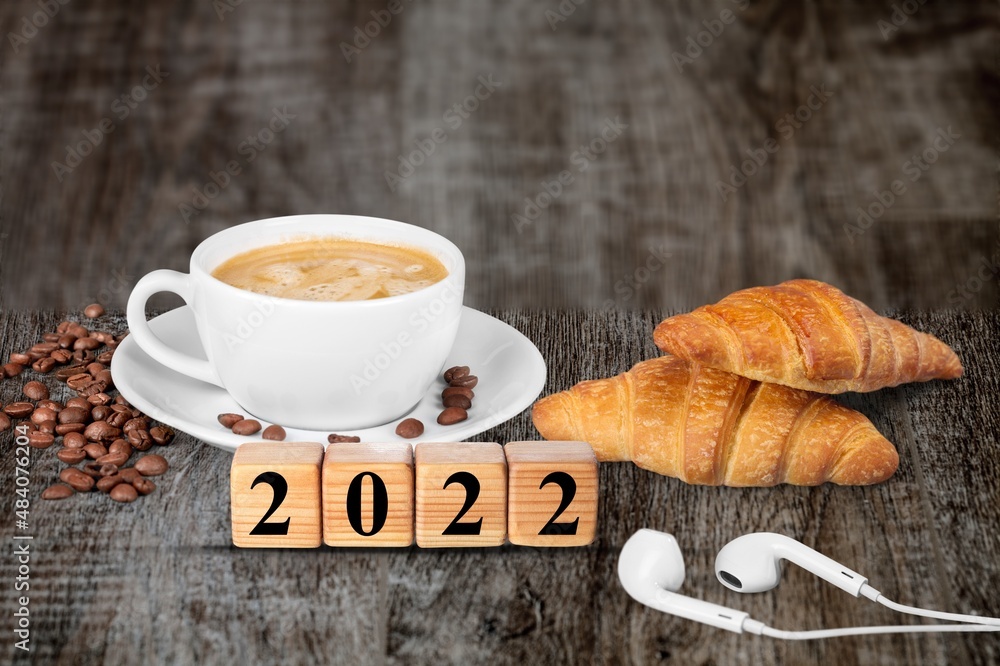 Wooden cubes with number 2022 on a table with coffee, croissant