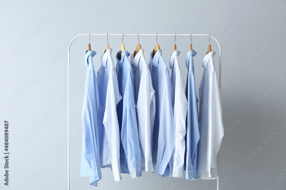 Rack with clean shirts on grey background