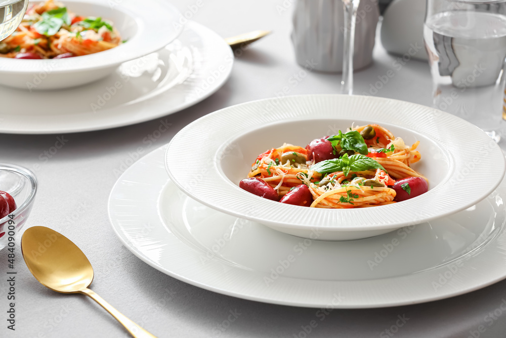 Plates of tasty Pasta Puttanesca on table in restaurant