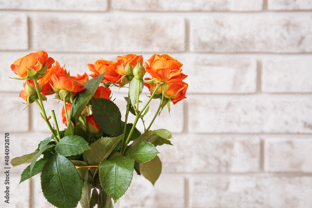 Bouquet of beautiful orange roses on brick background