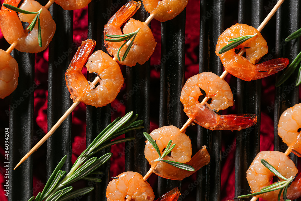 Skewers with delicious prawns and rosemary on grill, closeup