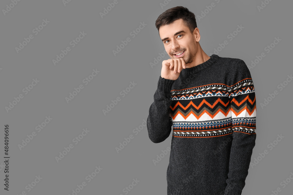 Handsome young man in knitted sweater on grey background