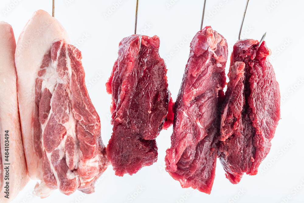 Fresh beef and pork hanging from a meat stall