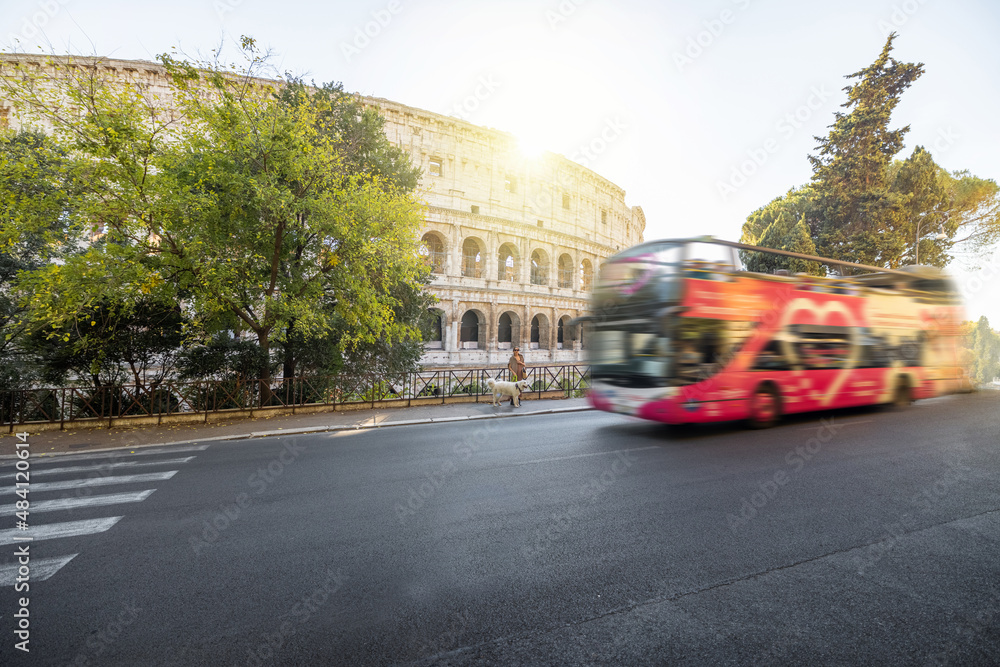 Street view with motion blurred tourist bus and Colosseum on background in Rome. Traveling Italian l