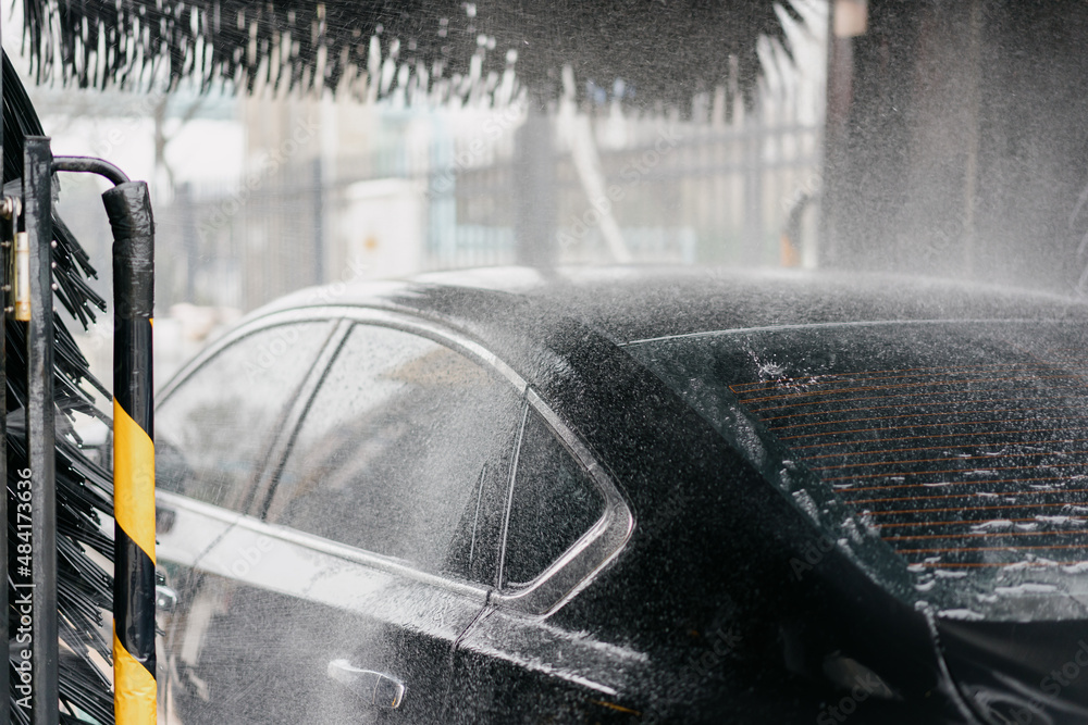 car washer washing car in parking lot