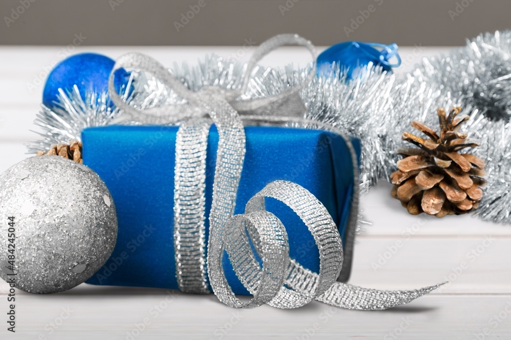 Wrapped Gift Box with a bow on a table with Christmas decorations around. Winter composition