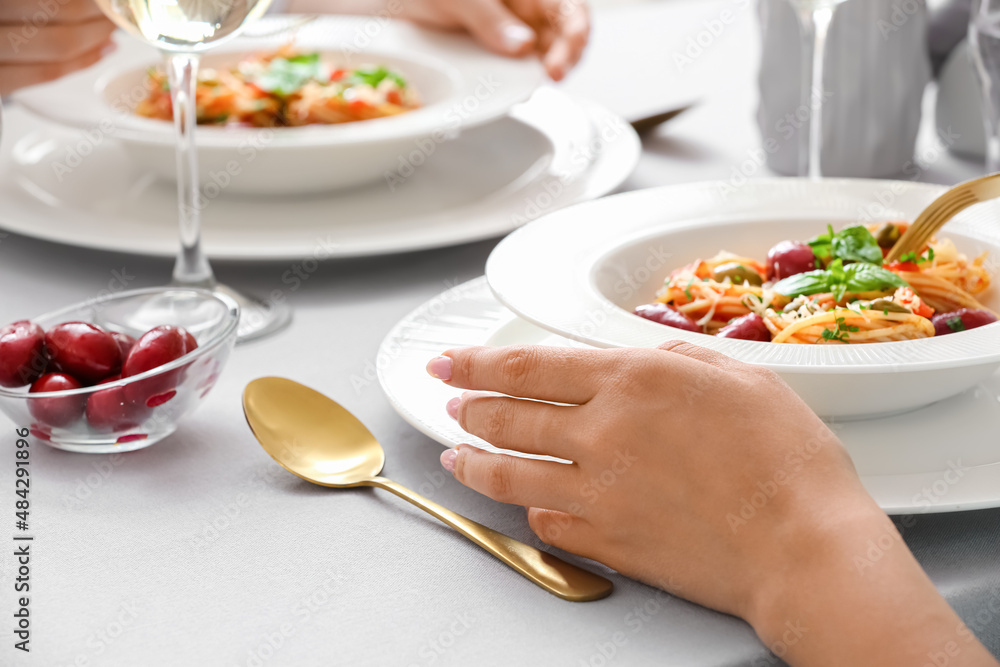 Woman eating Pasta Puttanesca at table in restaurant