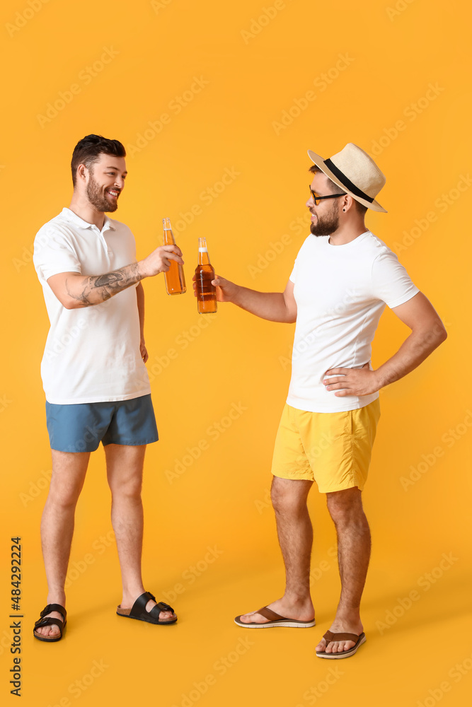 Young men with bottles of beer on yellow background