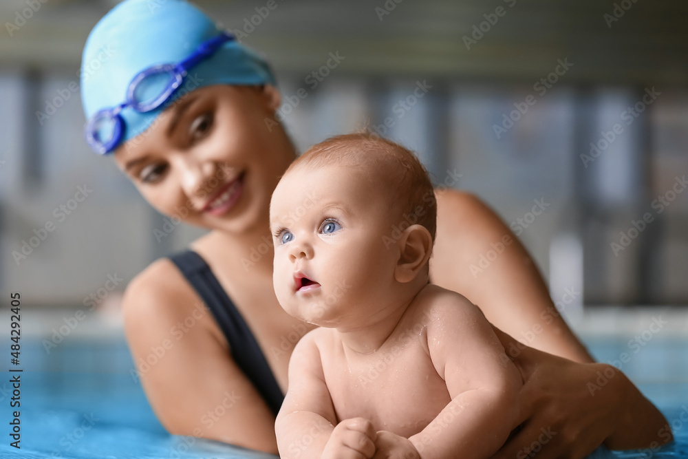 Adorable little baby with coach in swimming pool, closeup