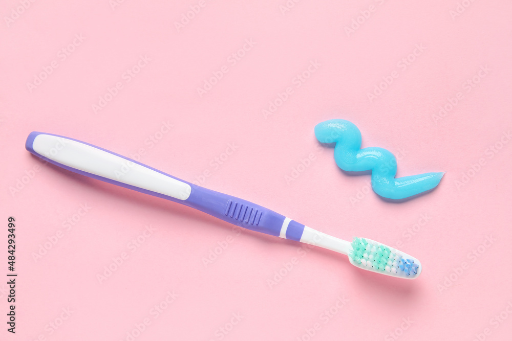 Sample of toothpaste and brush on pink background