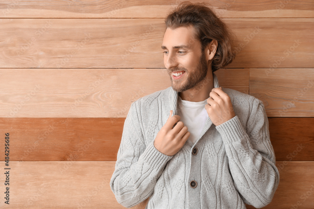 Handsome young man in knitted sweater on wooden background