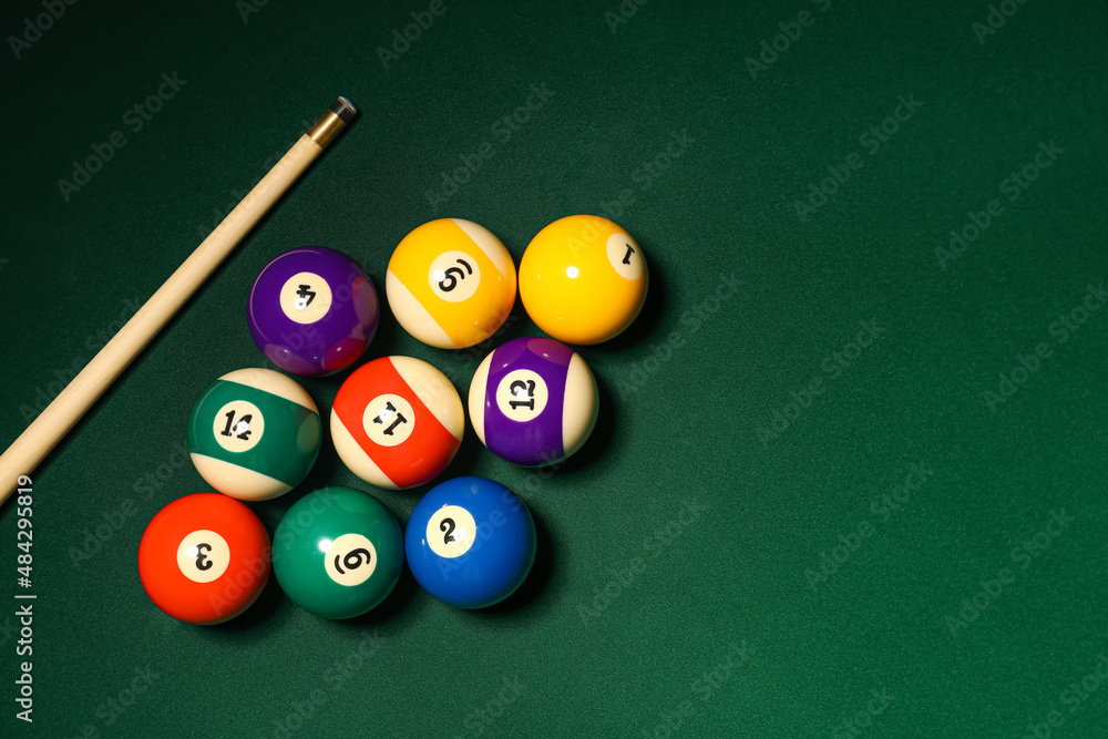 Different billiard balls with cue on green table