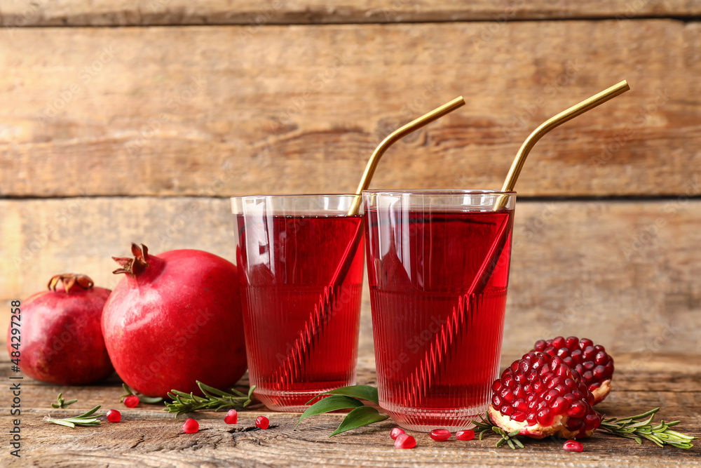 Glasses of delicious pomegranate juice on wooden background