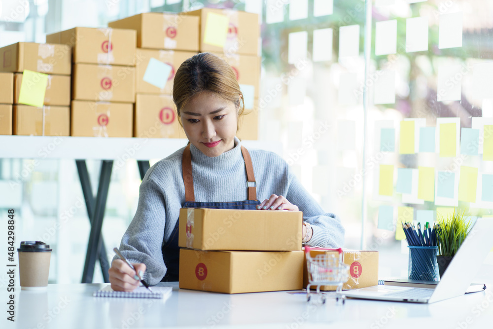 Online small business owner writing address on parcel box.