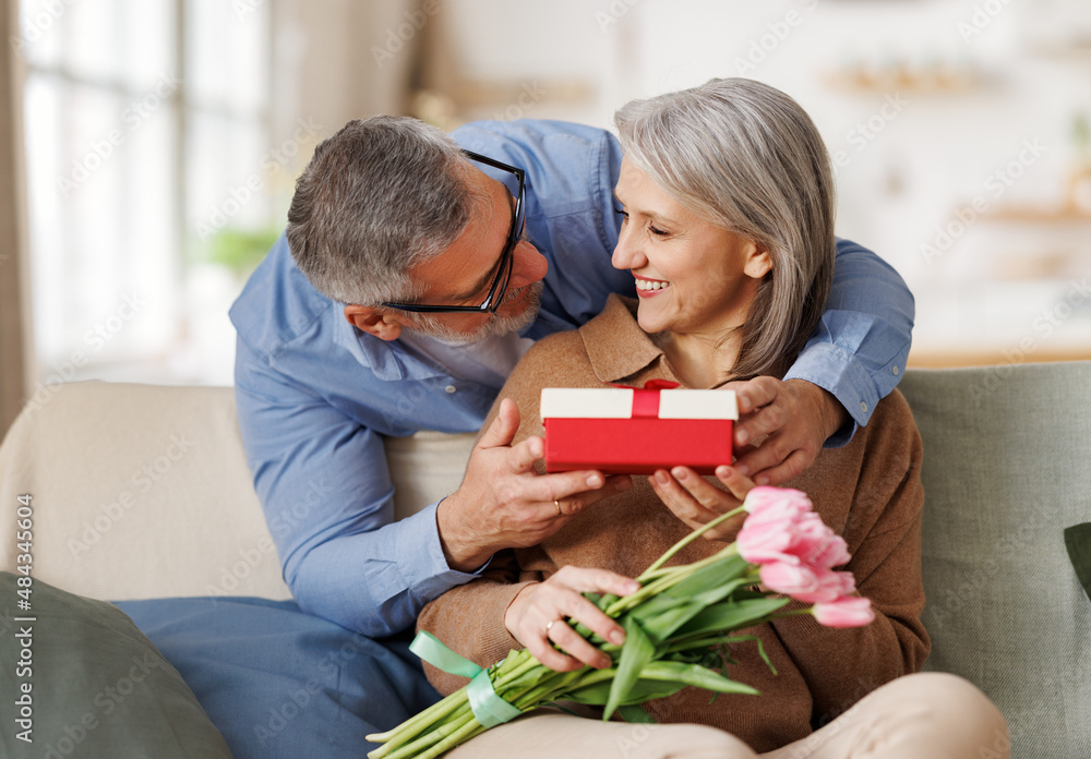 Loving    man husband giving  flowers and present gift box  for Valentines day   to happy surprised