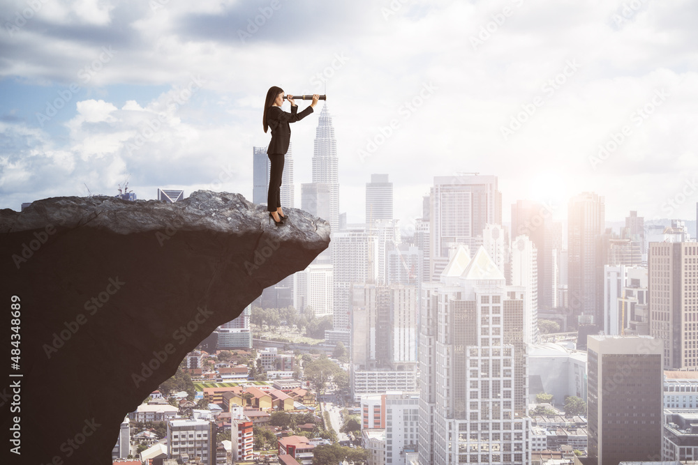 Attractive young european businesswoman with telescope on cliff edge looking into the distance on br