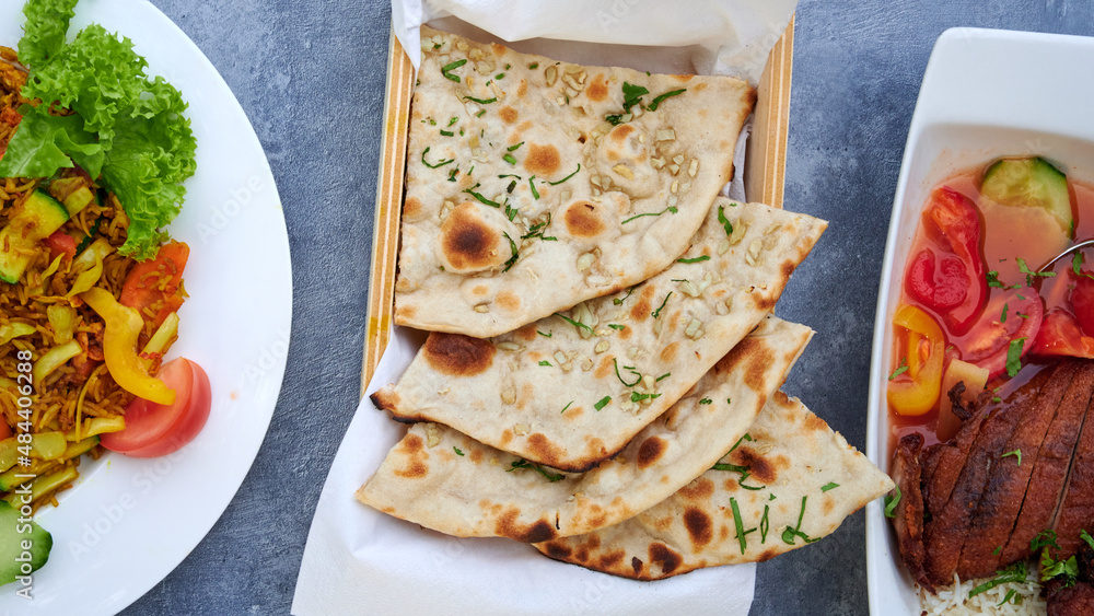 Leckeres indisches Naanbrot frisch aus dem tandoori Ofen in einer Schale mit Butter und Kräutern ser