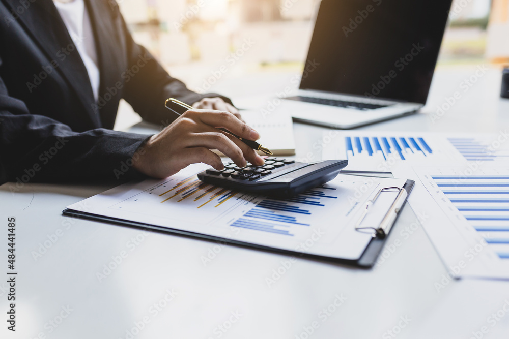 Businesswoman working on her desk using a calculator to calculate income and expenses to manage a bu