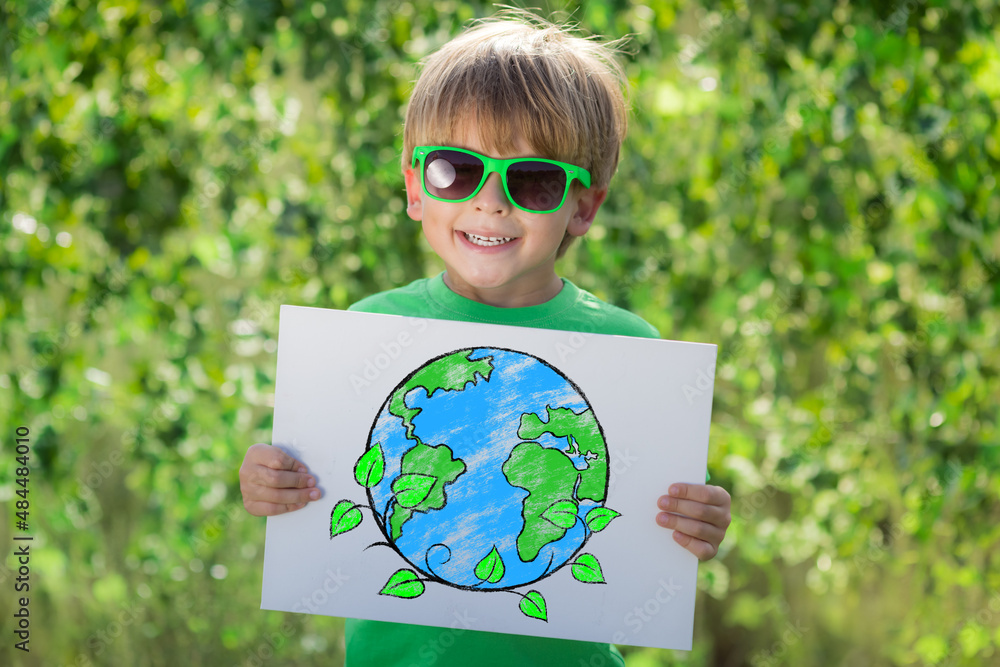 Happy child showing recycle sign outdoor in spring park