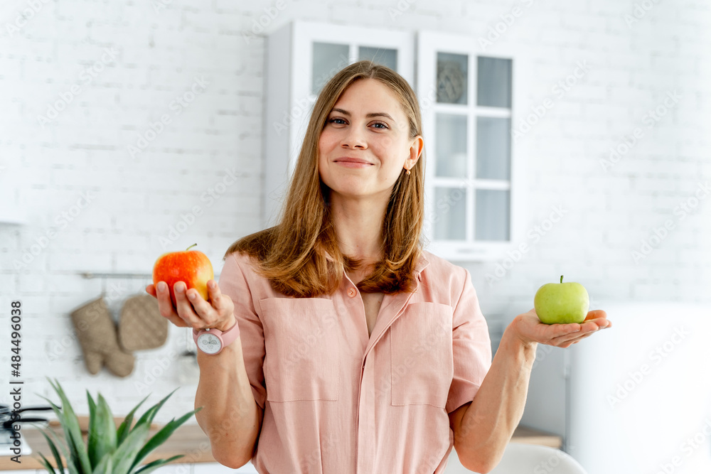 Cheerful beautiful woman looking into camera with apple. Playful pretty lady posing with healthy foo