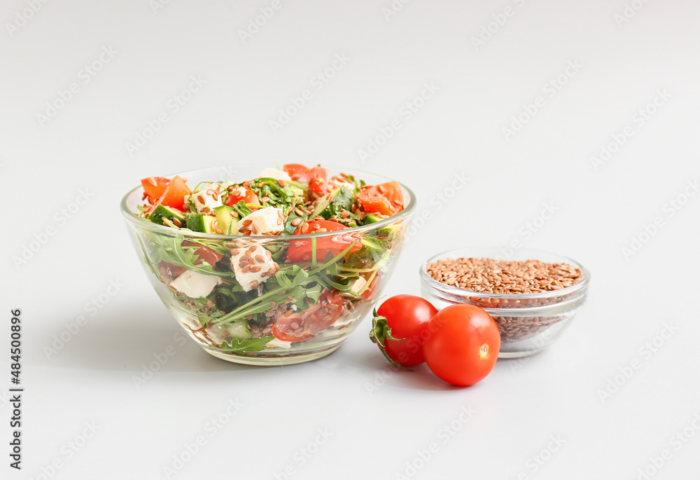 Bowl with healthy vegetable salad and flax seeds on light background