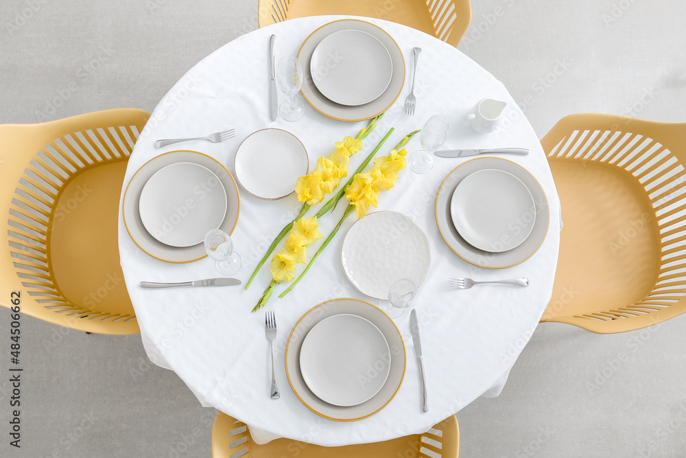 Beautiful table setting and Gladiolus flowers in room