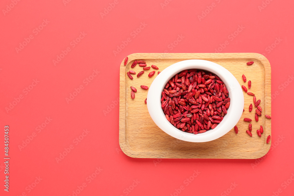 Bowl with dried barberries on red background