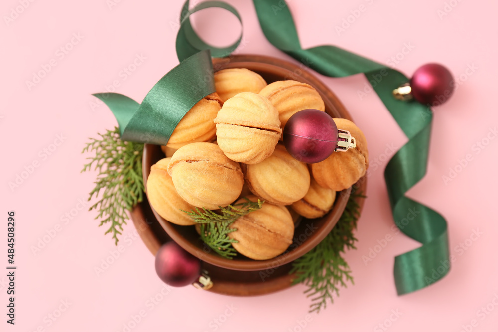 Bowl of walnut shaped cookies with boiled condensed milk, Christmas decorations and ribbon on color 