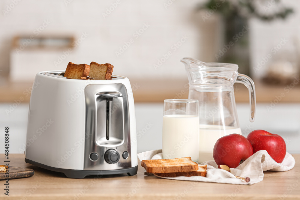 White toaster with apples and glass of milk on table in modern kitchen