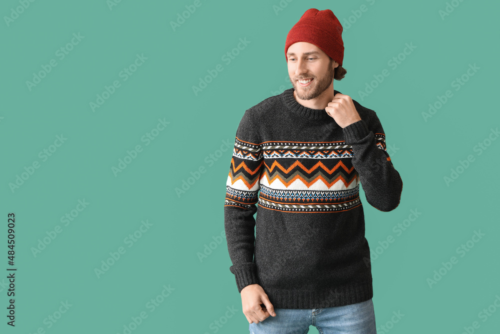 Handsome young man in knitted sweater on color background