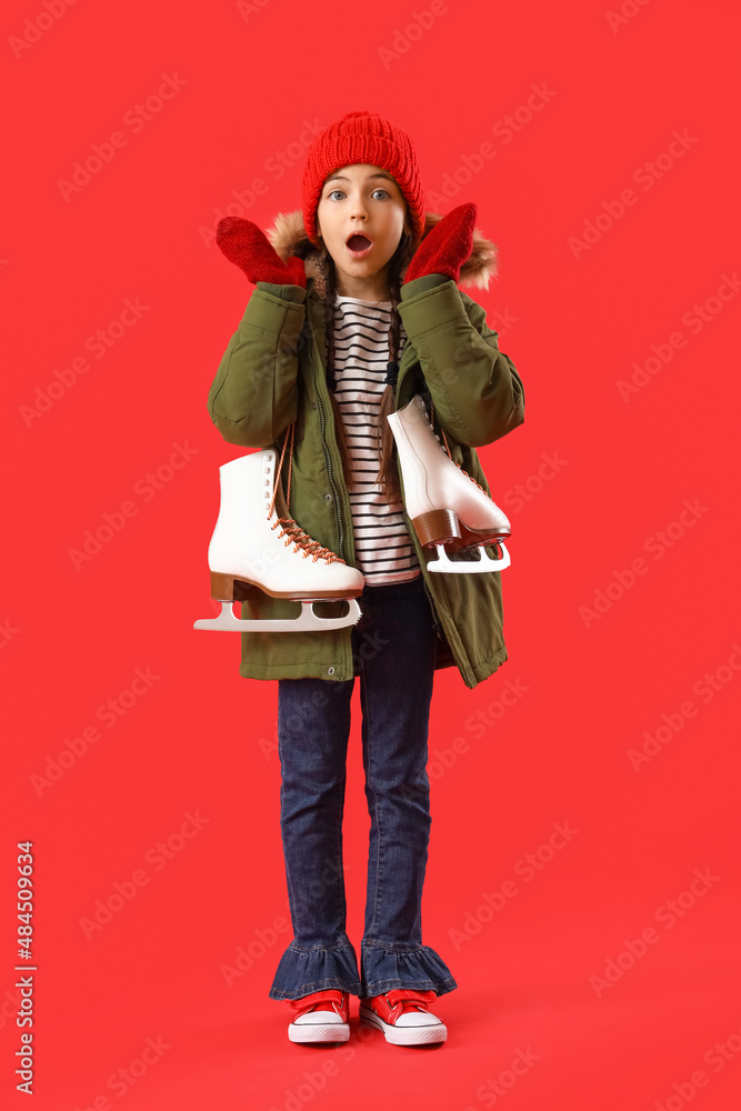 Surprised little girl with ice skates on color background