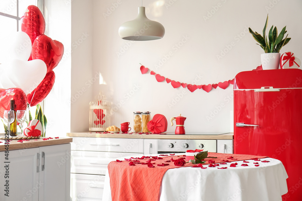 Dining table with rose, petals and gift box in kitchen decorated for Valentines Day celebration