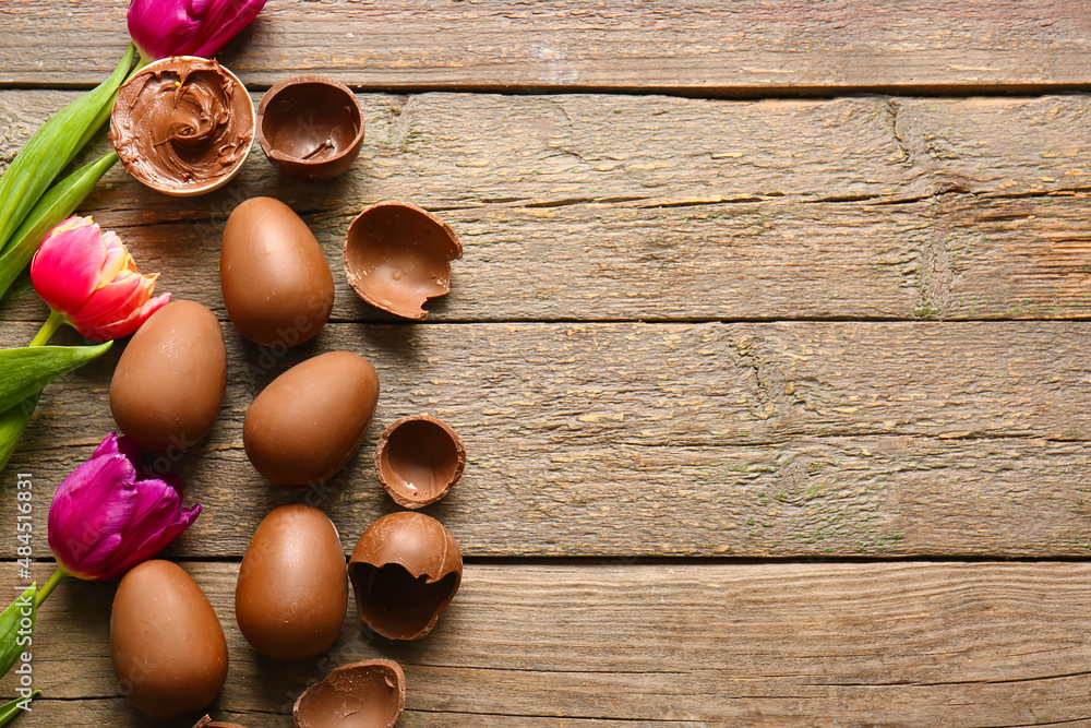 Chocolate Easter eggs and flowers on wooden background