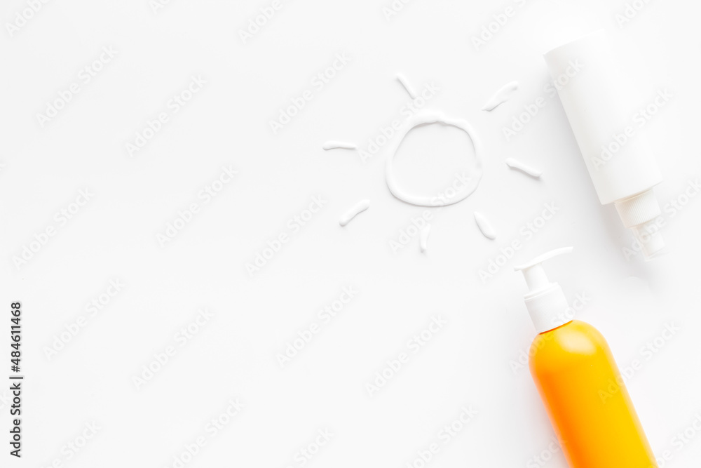 Sunscreen in bottles flatlay with sun made of white cream