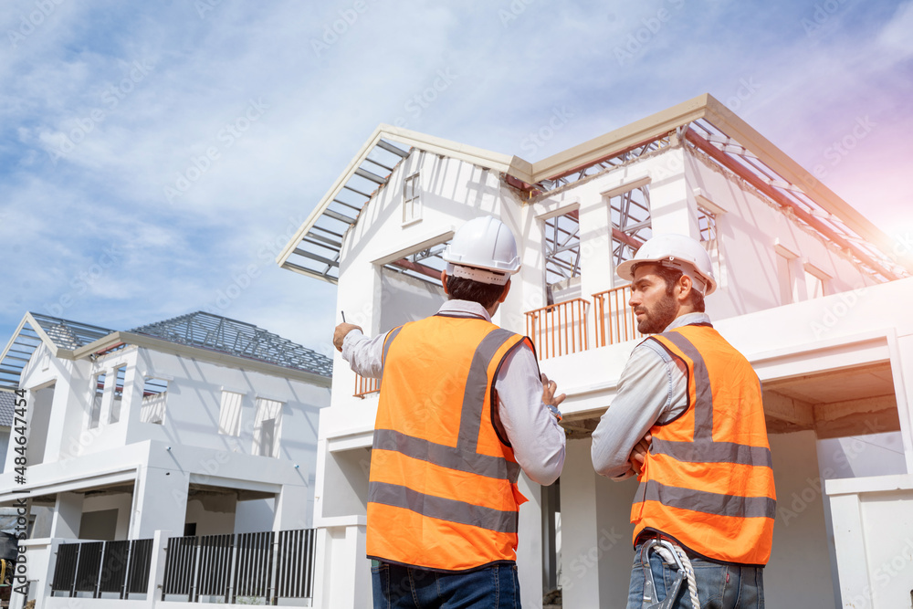 Architects discuss with head engineer about construction project on workplace at construction site.