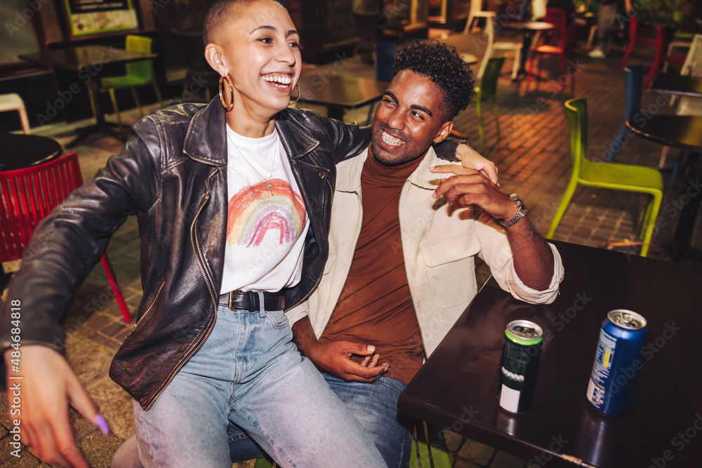 Two best friends laughing happily at an outdoor restaurant