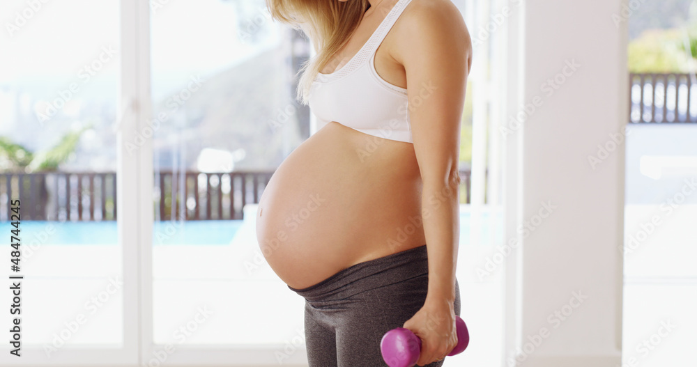 Strong mom = strong baby. Cropped shot of an unrecognizable young pregnant woman working out with du