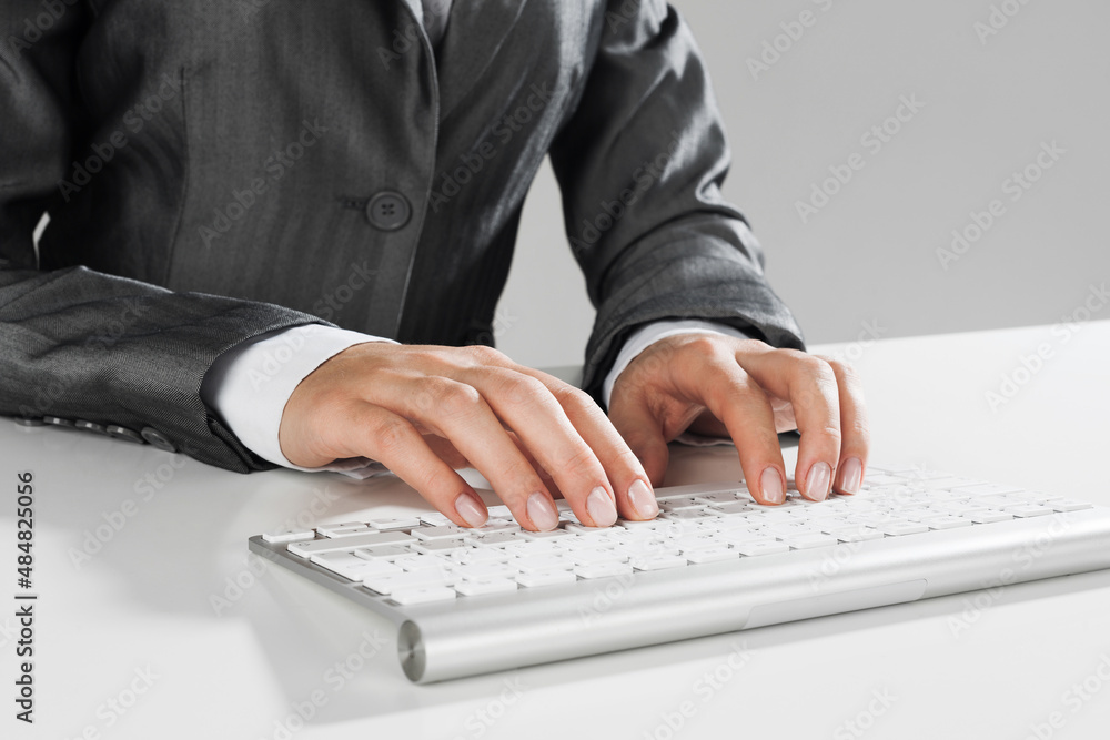 Closeup of businesswoman hand typing on keyboard with mouse on wood table