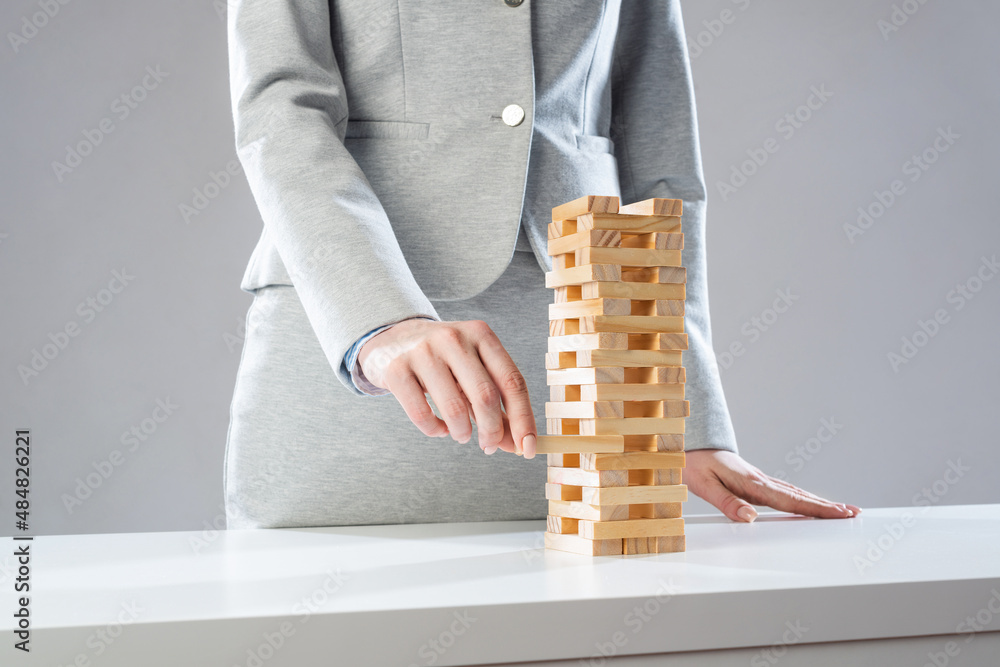 Businesswoman removing wooden block from tower