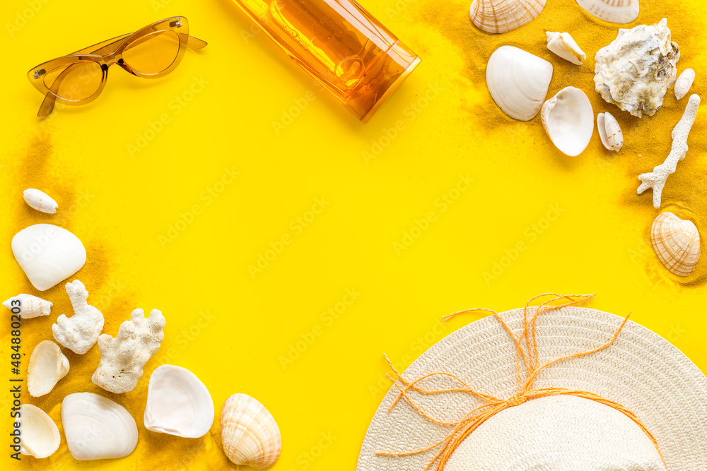 Beach sand and seashells with straw hat and bottles od sunscreen