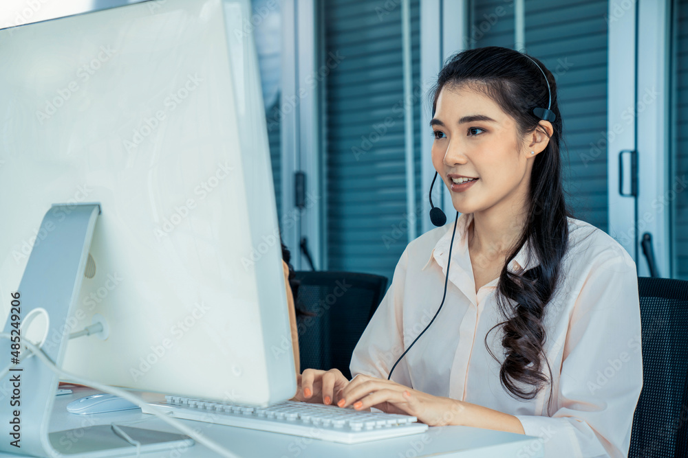 Businesswoman wearing headset working actively in office . Call center, telemarketing, customer supp