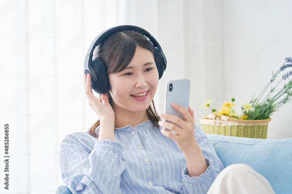 女性　スマホで音楽を聴く　リビング