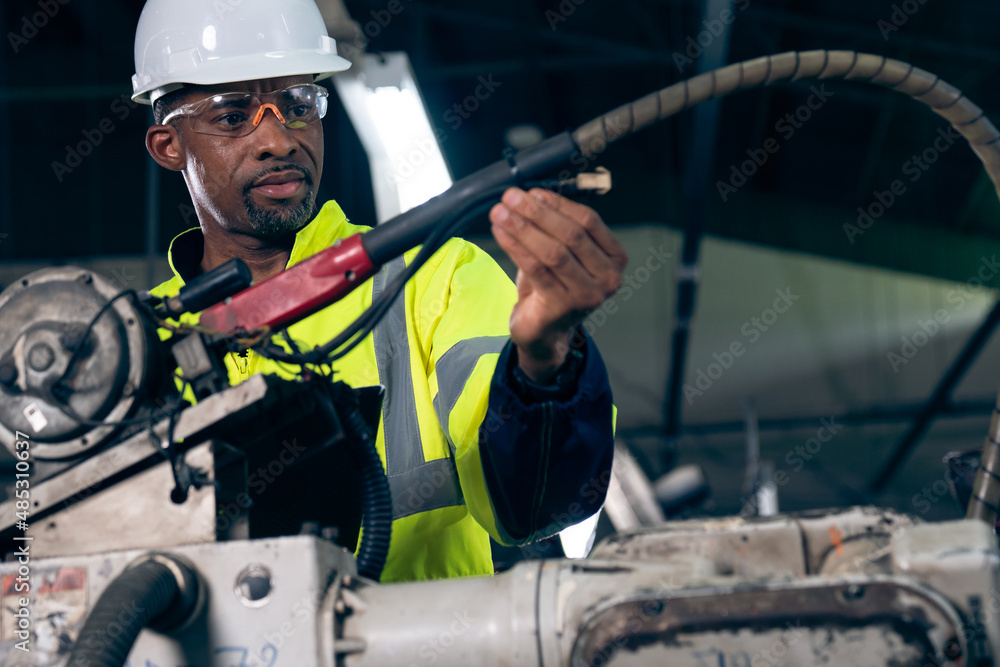 African American factory worker working with adept robotic arm in a workshop . Industry robot progra