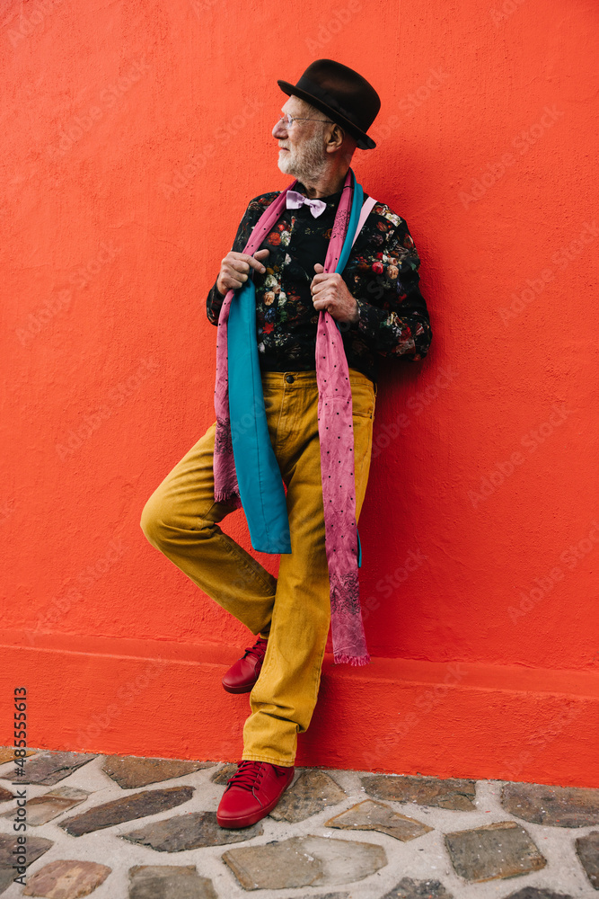 Senior man looking away thoughtfully against a red wall