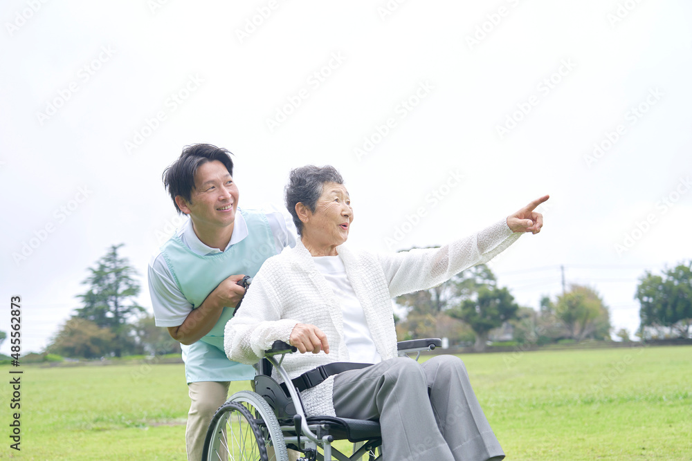 介護士と車椅子に乗る高齢者　屋外