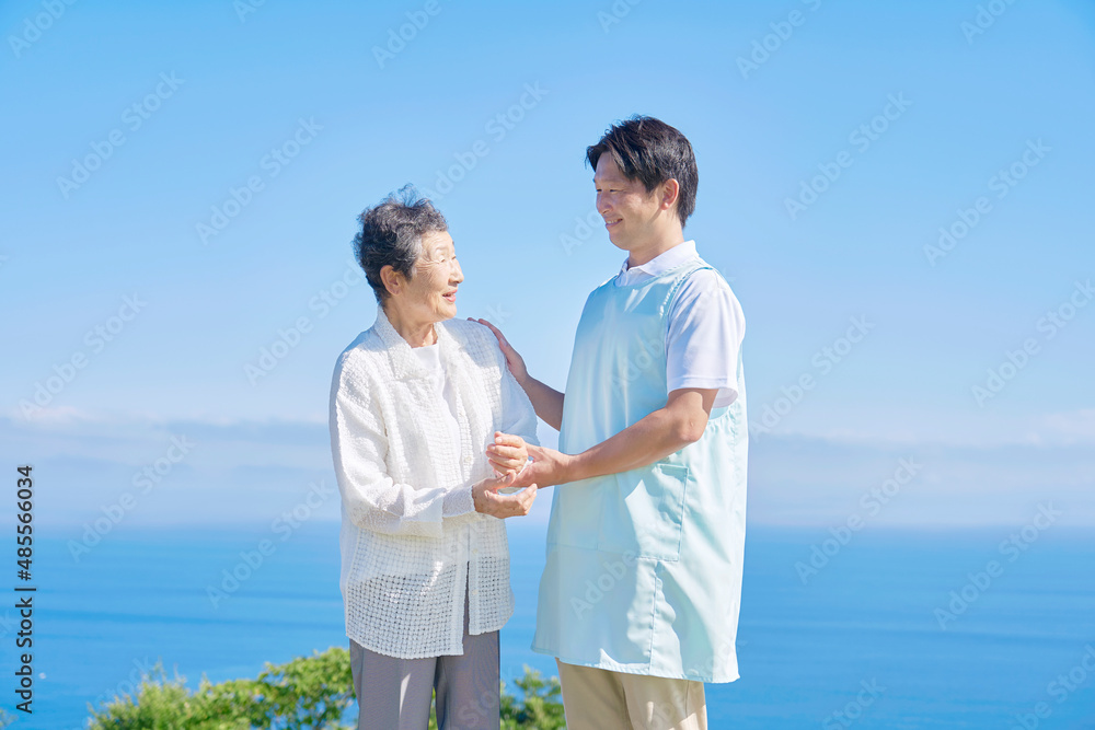 介護士と車椅子に乗る高齢者　屋外