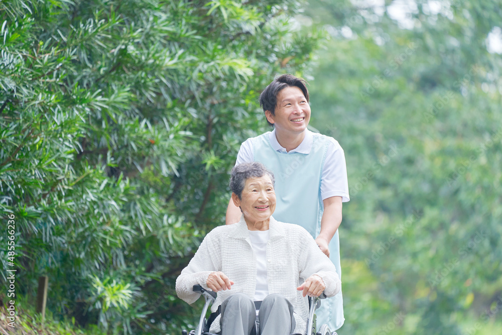 介護士と車椅子に乗る高齢者　屋外